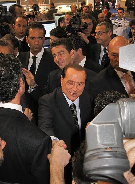 Berlusca.jpg - [it]Silvio Berlusconi al Salone moto Eicma di Milano, 2008, fotografato grazie allo schermo LCD orientabile[en]Silvio Berlusconi (1936-2056 in his own hope), italian prime minister and TV tycoon, at Motorcycle Show Eicma 2008 in Milan. A difficult subject due to pocket size, so I used the tiltable LCD